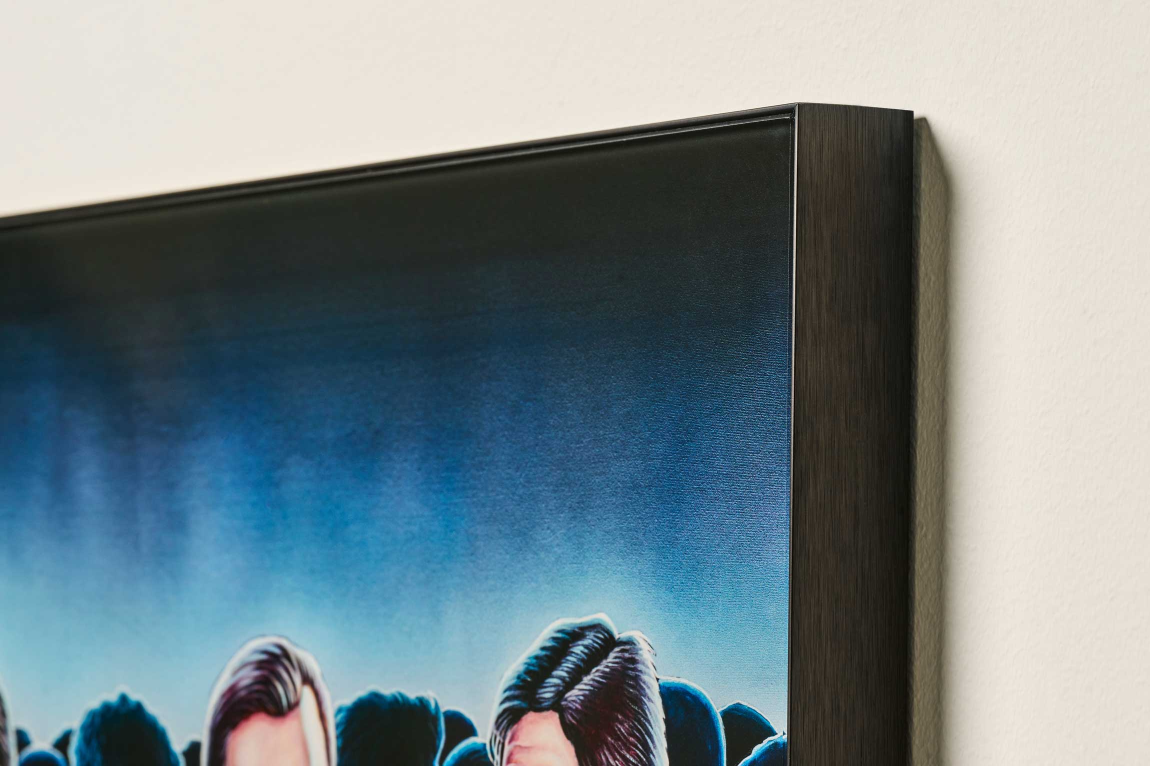 Framed artwork of a crowd against a blue sky on a beige wall