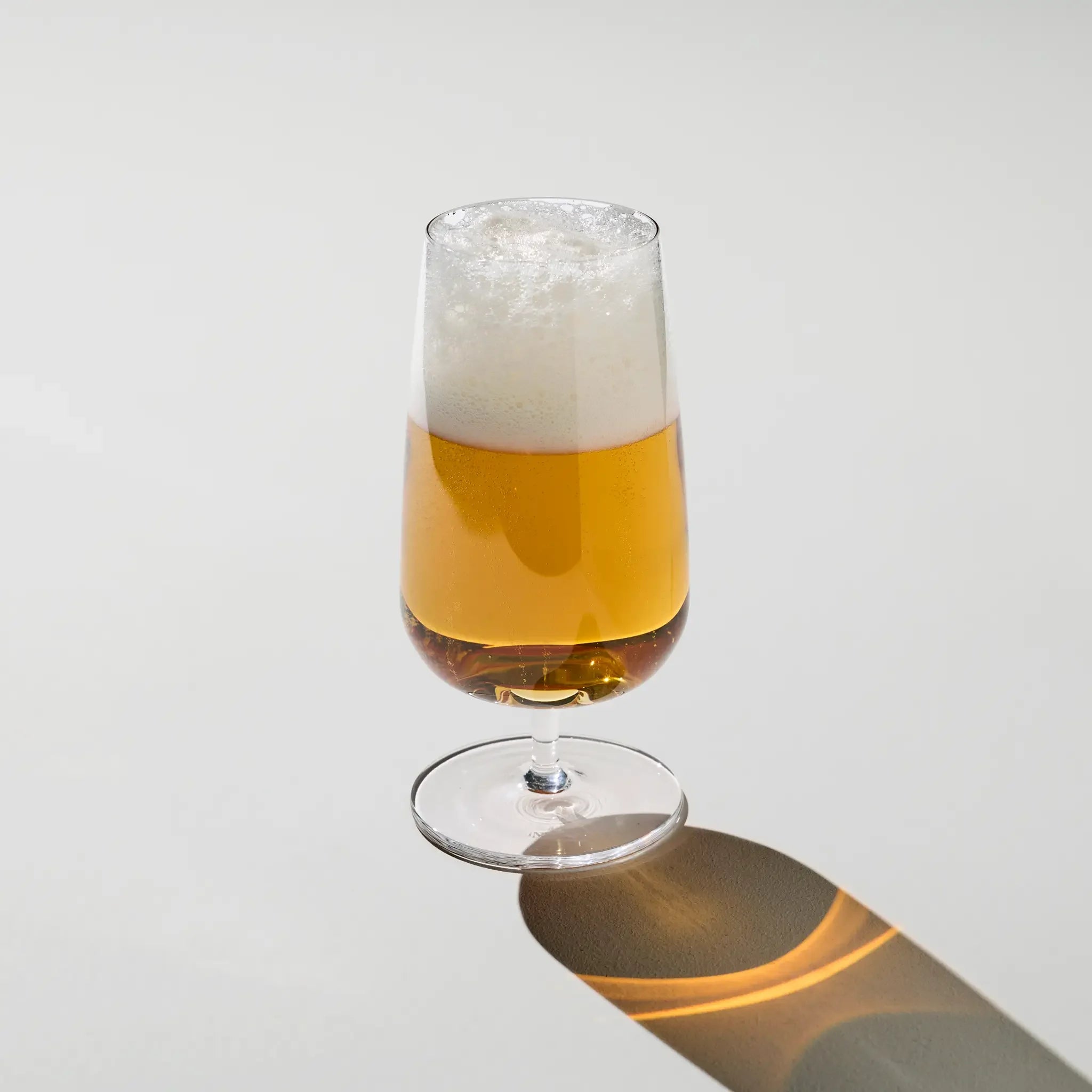 Brewer’s Beer Glass filled with golden pilsner – slim, tall glass with foamy head, showcasing clarity and carbonation in bold style.