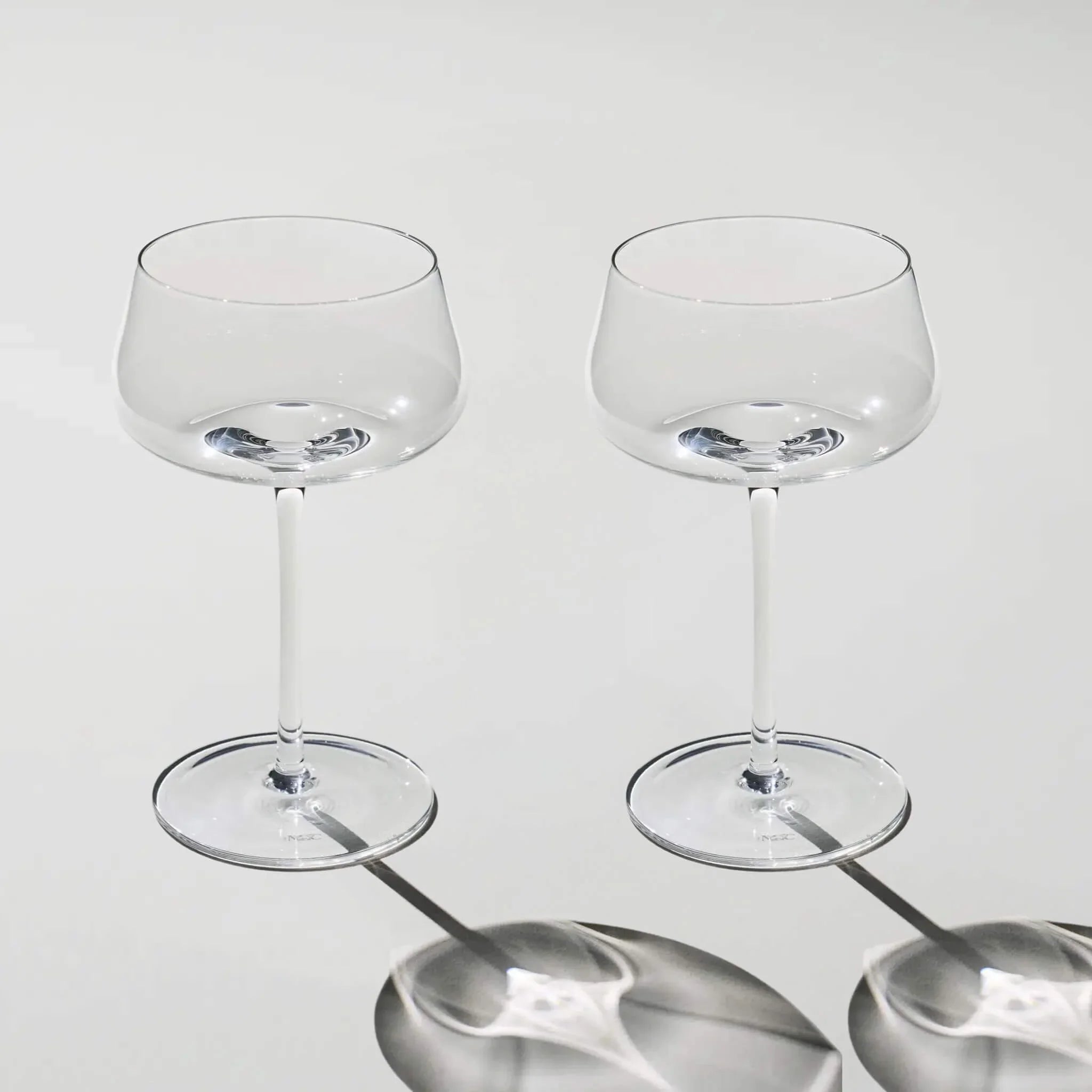 Two clear wine glasses on a light gray background